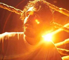 a man standing in front of a fence with the sun shining down on his face