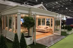 a room filled with furniture and plants on display at a trade show in an indoor building