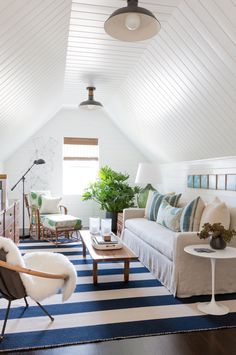 a living room filled with furniture and a blue and white striped rug on top of a hard wood floor