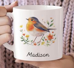 a person holding a coffee mug with a bird on it and the words madison written in black