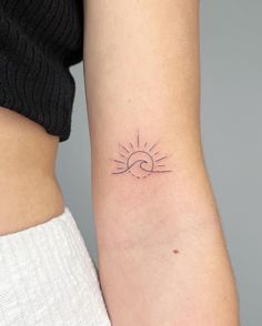 a woman's arm with a small sun and wave tattoo on the left side