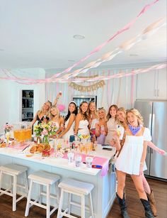 a group of women standing in front of a table with drinks and food on it