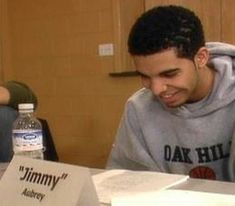 a man sitting at a table with a pizza box in front of him and a bottle of water behind him