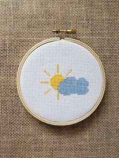 a cross - stitch sun and cloud on a white background is shown in the hoop