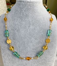 Stunning Art Deco-inspired necklace handmade with vintage-style Czech glass beads and gold-plated findings. This 17.5-inch necklace features a beautiful combination of gold, blue, green, yellow, orange, and translucent beads that are sure to catch the eye of everyone in the room. The large blue beads are even wire-wrapped, adding an extra touch of elegance and texture. The necklace is perfect for women who want to make a statement with their accessories, whether it's for a special occasion or ju Unique Gold Beaded Necklaces With Spacer Beads, Unique Gold Beaded Chain Necklace, Gold Glass Beaded Chain Necklaces, Gold Beaded Glass Necklace, Gold Glass Beaded Necklace, Turquoise Wire Wrapped Glass Necklaces, Turquoise Glass Wire Wrapped Necklace, Bohemian Gold Beaded Glass Necklaces, Wire Wrapped Round Glass Beaded Necklaces