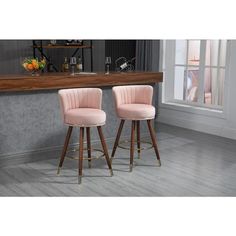 two pink velvet bar stools in front of a counter with a wine glass on it