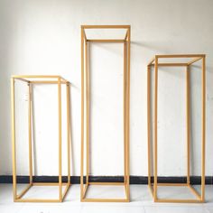 three golden frames against a white wall in an empty room with no one inside them