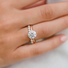 a woman's hand with a diamond ring on top of her finger and an engagement band