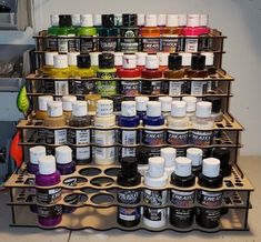 a shelf filled with lots of different types of paint and ink bottles on it's sides