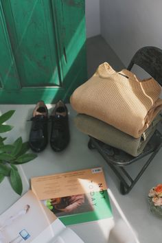 a stack of folded clothes sitting on top of a chair next to a green door