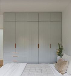 a white bed sitting in a bedroom next to tall cabinets