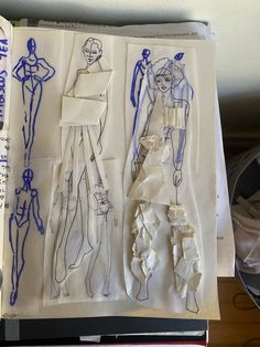 an open book with paper cut out of mannequins and clothes on it