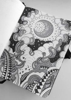 an open notebook with black and white doodles on the cover, sitting on top of a table