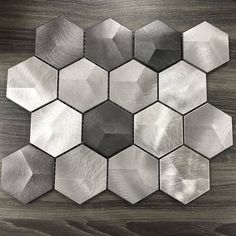 the hexagonal metal tiles are arranged on a wooden surface, which has been painted silver