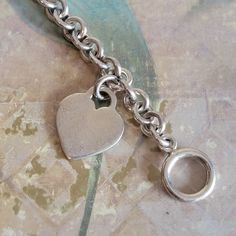 This is a vintage, sterling silver, link, bracelet with a toggle clasp and heart pendant/charm. This has tested positive for sterling silver. There is some wear/superficial scratches to the heart, as you can see in the images. All sales are final. This measures 7.25 inches in length x 8 mm in width. The heart is 1 and 1/8 inches in length including the bale. If you have a wish list or are looking for something specific, please ask. I may have exactly what you are looking for. As always please convo me with any questions or concerns regarding this item or with any international shipping questions. Unfortunately I do not accept returns or grant refunds. All shipping fees include handling fees. If you would like to combine shipping costs for more than one item, I would be happy to do so if yo Vintage Sterling Silver Bracelet With Heart Charm, Sterling Silver Charm Bracelet With Toggle Clasp, Everyday Vintage Sterling Silver Bracelet, Vintage Silver Bracelet With Heart Charm, Vintage Silver Bracelets With Heart Charm, Vintage Sterling Silver Everyday Bracelets, Vintage Sterling Silver Everyday Bracelet, Vintage Sterling Silver Bracelets For Everyday, Sterling Silver Heart Bracelet With Charms