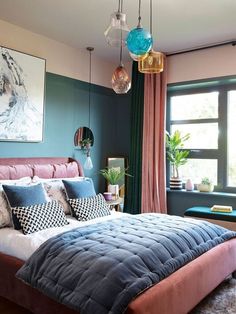 a bedroom with blue walls, pink bedding and hanging lights over the headboard