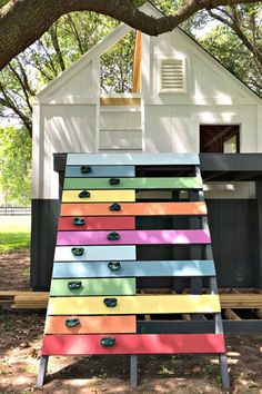 a multicolored dresser sitting in front of a tree