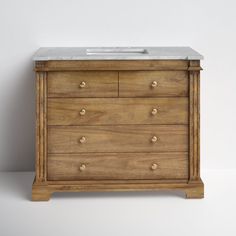 a bathroom vanity with marble top and wooden drawers on the bottom, against a white wall