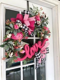 a wreath with the word love is hanging on a window sill in front of a white door