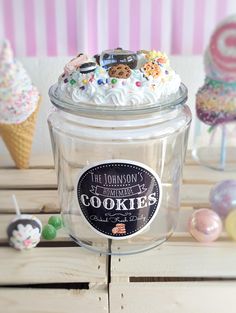 a glass jar filled with cookies on top of a wooden table next to other desserts