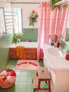 a bathroom with green tile and pink curtains