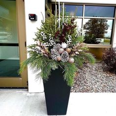 a planter filled with pine cones and evergreens on the side of a building