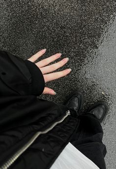 a person's hand on the ground next to a black jacket and white pants