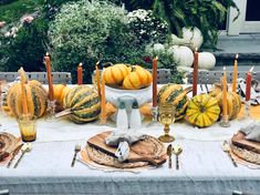 a table set up with pumpkins and candles for an outdoor dinner or party in the garden