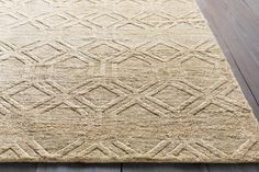 a beige rug with an intricate design on the top and bottom, sitting on a wooden floor