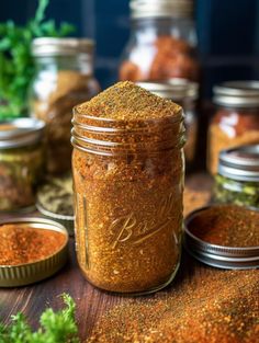 several jars filled with spices on top of a wooden table next to some parsley