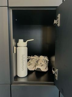 a white water bottle sitting on top of a metal shelf next to shoes in a locker