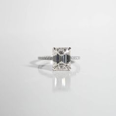 an emerald cut diamond ring on a white surface