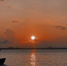 the sun is setting over the ocean with a sailboat in the foreground and clouds in the background