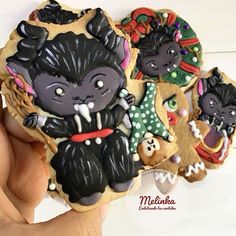 a hand is holding some decorated cookies in the shape of animals and witches on them