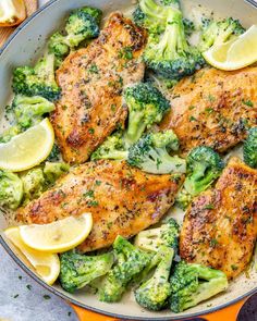 chicken and broccoli in a skillet with lemon wedges on the side