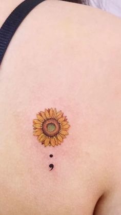 a small sunflower tattoo on the back of a woman's left shoulder,