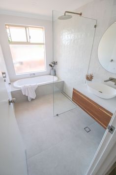 a bathroom with a sink, mirror and bathtub next to a window in it