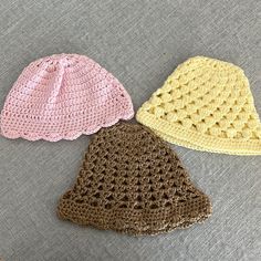 three crocheted hats sitting on top of a gray couch next to each other