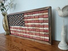 an american flag made out of wine corks on top of a wooden table next to a vase with flowers