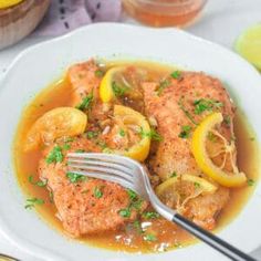 a white bowl filled with fish and lemons next to some bread on a table