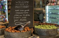 there is a sign that says welcome to the nutteryy shop and it has many different types of nuts