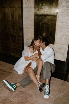 a man and woman are sitting on the floor kissing while they both have their hands around each other