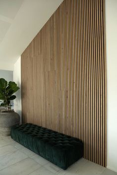 a green bench sitting in front of a wooden wall with vertical slats on it