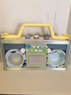 an old fashioned toy radio with its speakers and lights on it's side, in front of a white wall