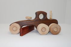 a wooden toy train with wheels and wood handles sitting on a white surface, in front of a plain background