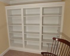 an empty room with a rocking chair and bookcases