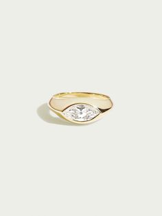 a gold ring with an oval shaped diamond in the center and a small white diamond on top