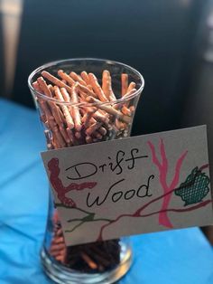 a glass filled with lots of different types of wood sticks in front of a sign that says driftwood