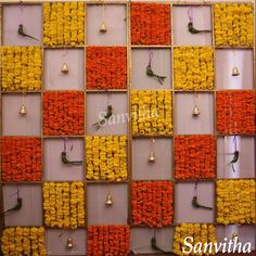 the wall is made up of orange and yellow flowers with birds hanging from each side