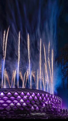 fireworks are lit up in the night sky above an olympic stadium